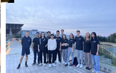 Students in matching t-shirts gathered on a rooftop at dusk