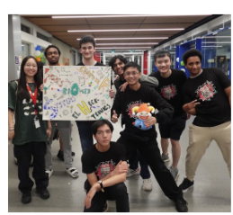 Students holding up a colourful poster with a large letter M