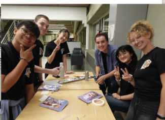 Students gathered around a table smiling at the camera