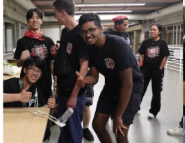 A group of students giving a thumbs up in a campus hallway